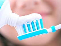 closeup of person putting toothpaste on toothbrush 