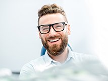 man smiling while sitting in dental chair 